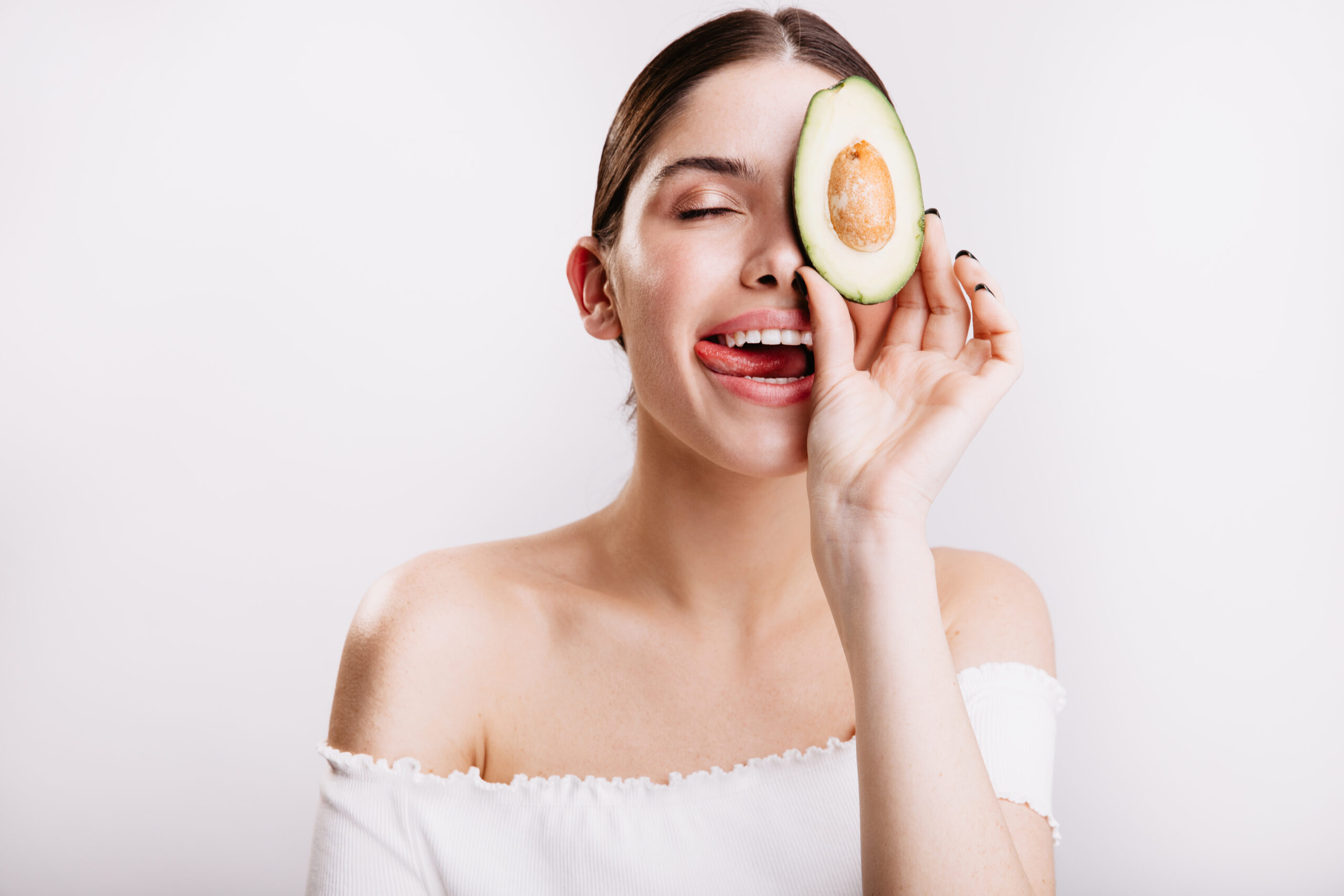 Freepik imagem: Jovem segurando abacate no rosto.