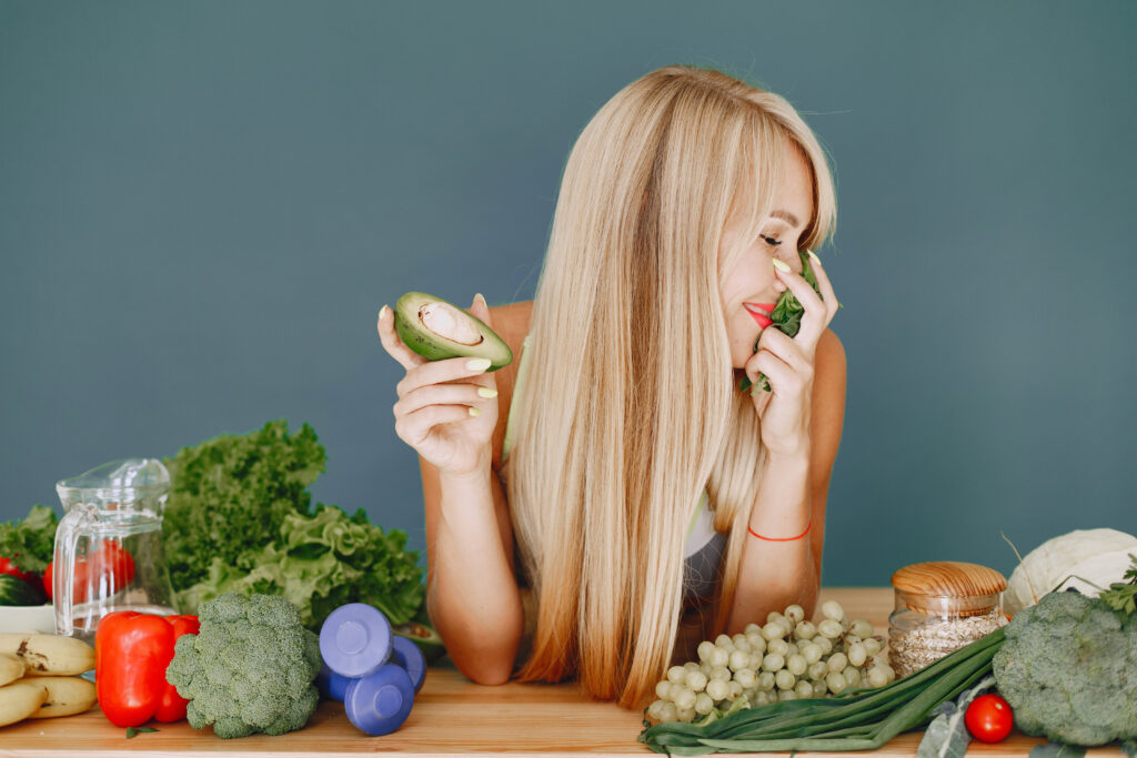 Freepik imagem: mulher com cabelos bonitos em meio a uma mesa de alimentos saudáveis.