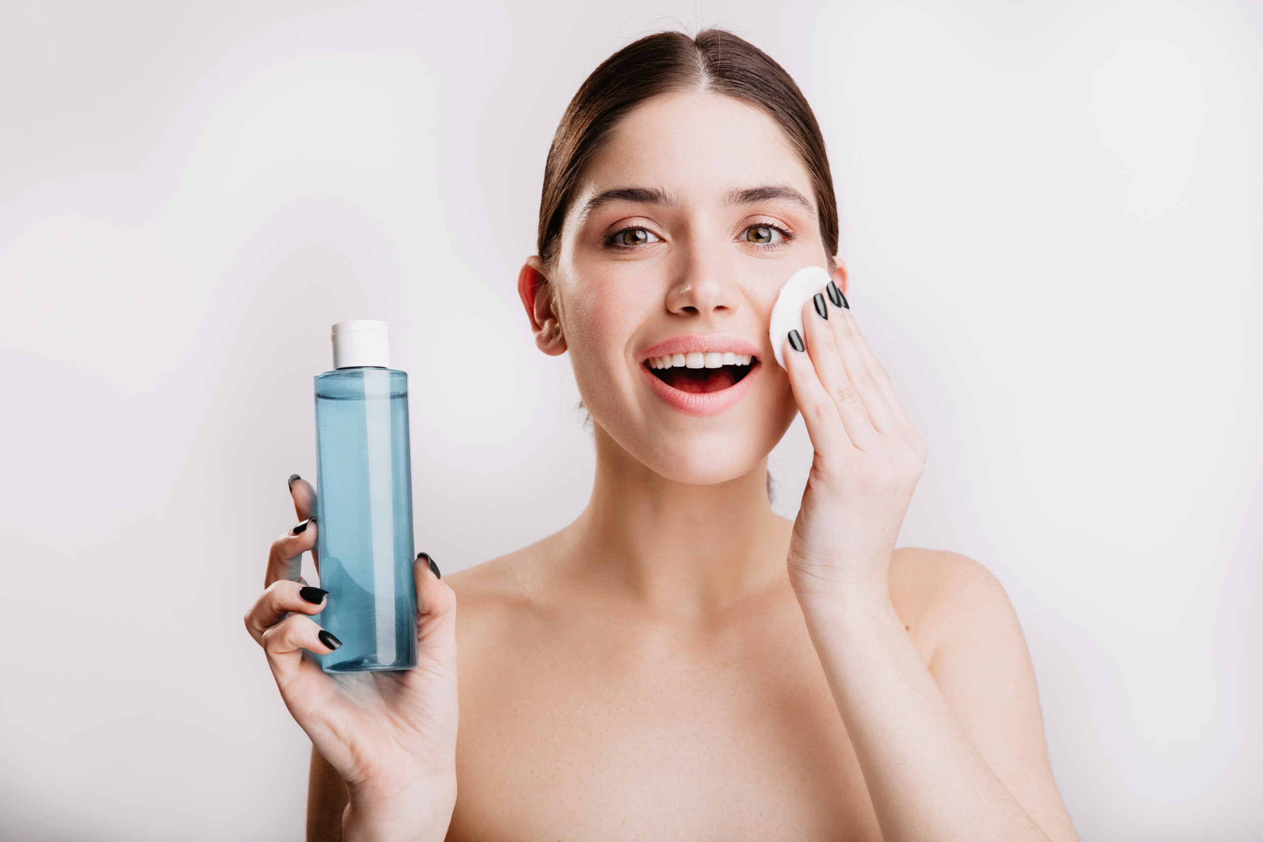Freepik imagem: mulher jovem bonita passando água micelar no rosto.