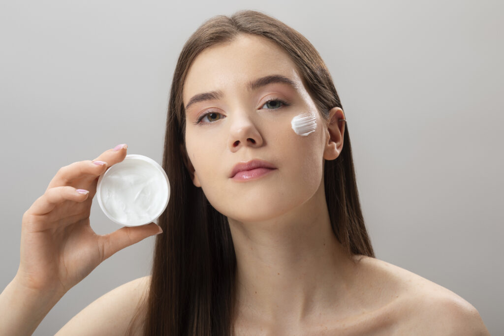 Freepik imagem: mulher jovem usando hidratante facial.