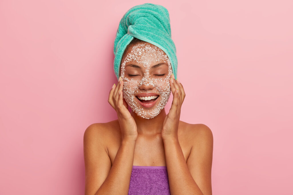 Freepik imagem: mulher jovem fazendo esfoliação no rosto.
