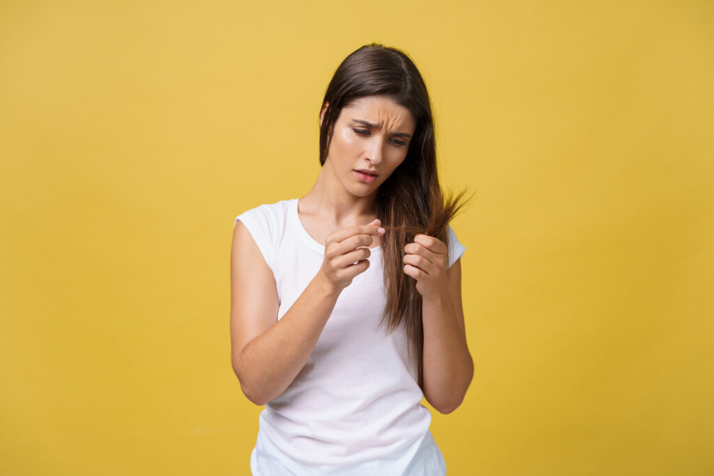 Freepik imagem: mulher preocupada com os cabelos danificados.