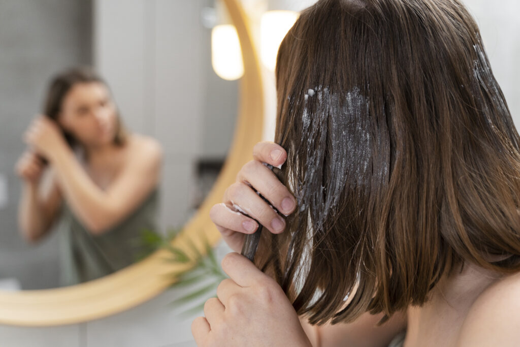 Freepik imagem: mulher jovem fazendo nutrição nos cabelos em casa.