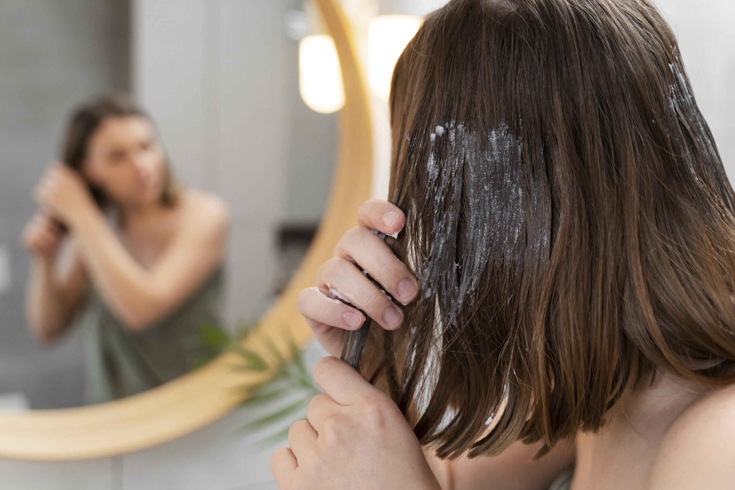 Freepik imagem: mulher jovem fazendo nutrição nos cabelos em casa.